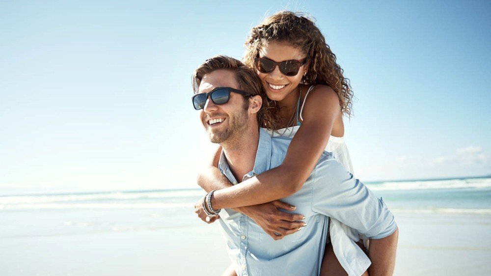 Ungt parr på stranden med solbriller