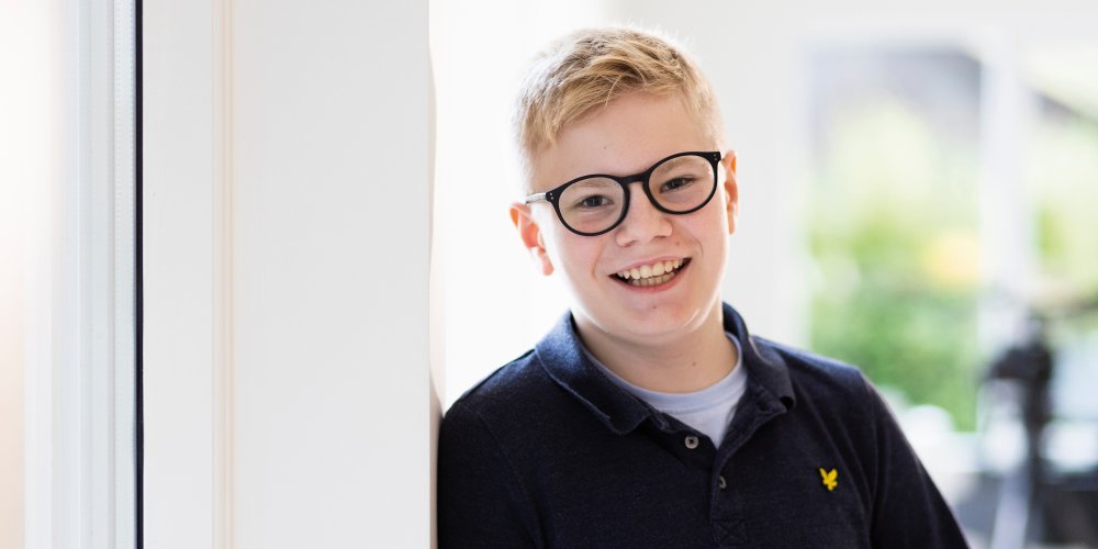 Ung gutt smiler iført MiYOSMART-briller som bremser nærsynthet hos barn