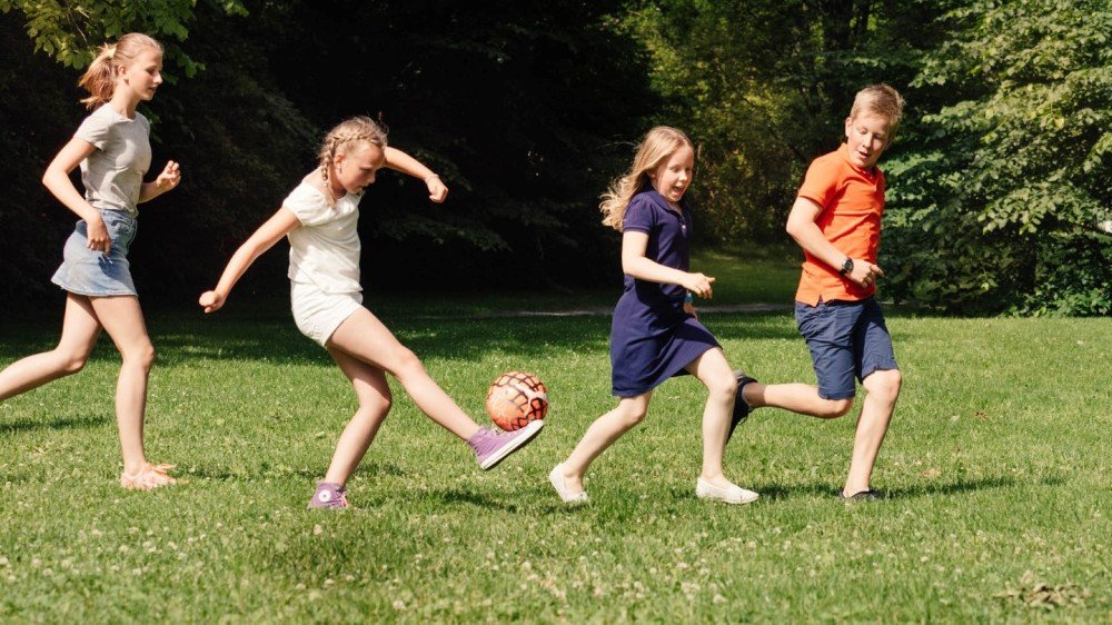 Barn som spiller fotball i parken