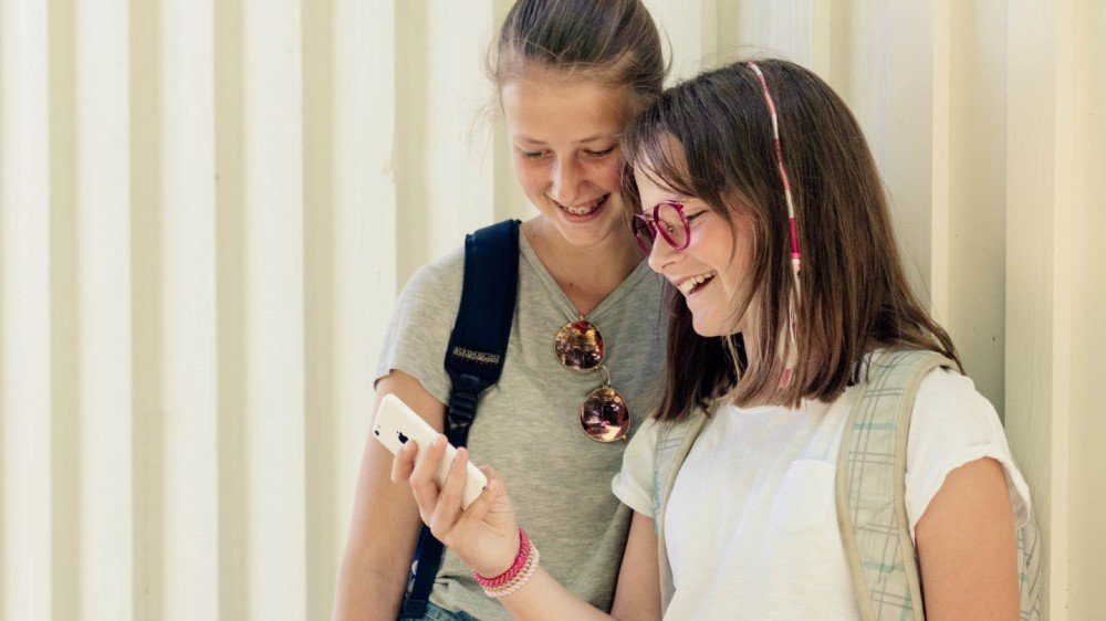 Unge jenter med briller som leser på mobil