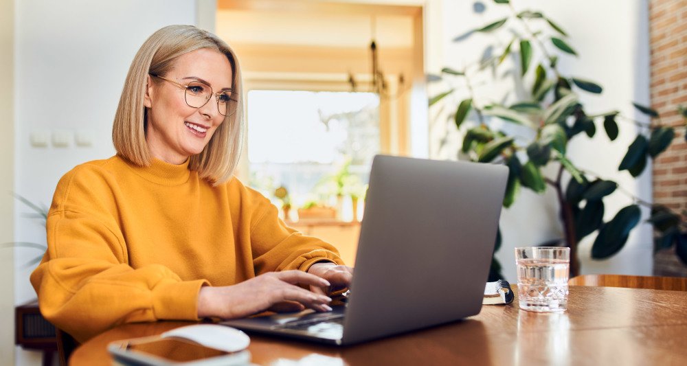 Kvinne med databriller foran pc-skjerm på jobb