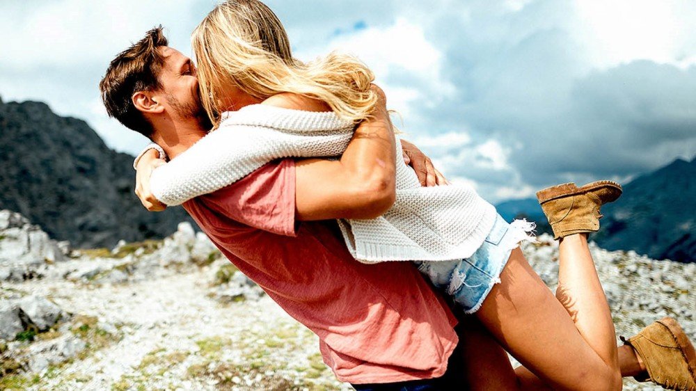 Ungt parr kyssende på fjellet